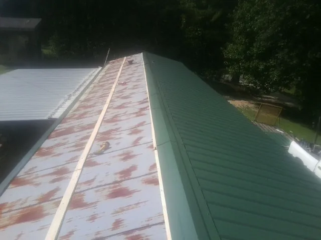 Old rusted panels beside newly installed green metal roofing — Wind Damage Roof Repair by Roofing Brothers in Austin